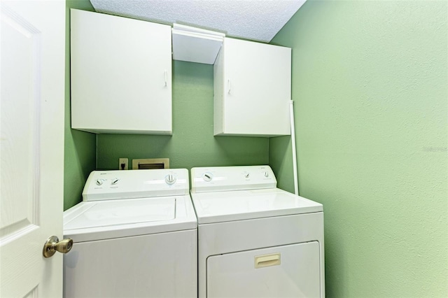 washroom with cabinets, a textured ceiling, and independent washer and dryer