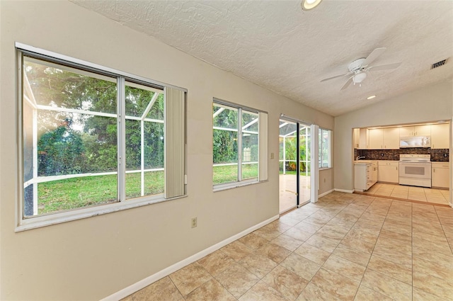 interior space featuring vaulted ceiling, white cabinets, white appliances, a textured ceiling, and ceiling fan