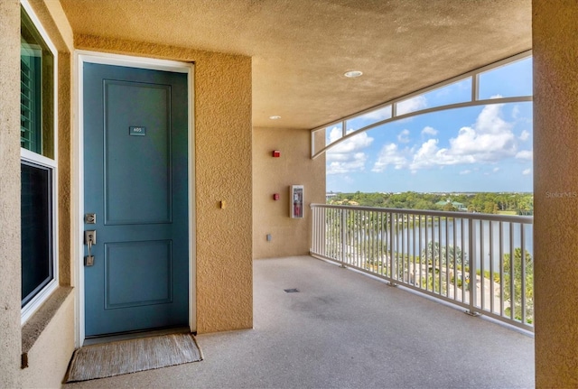 exterior space with a water view, a balcony, and stucco siding