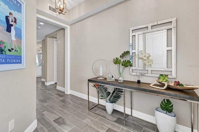 corridor featuring baseboards, a notable chandelier, and visible vents