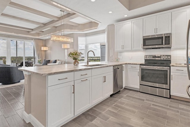 kitchen with a peninsula, a sink, stainless steel appliances, tasteful backsplash, and recessed lighting