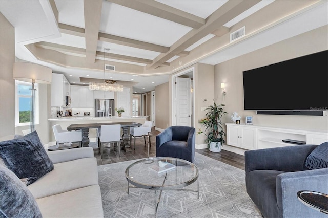 living room with wood-type flooring, beamed ceiling, an inviting chandelier, and coffered ceiling