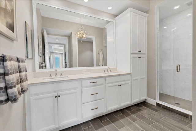 bathroom with a stall shower, a chandelier, and a sink