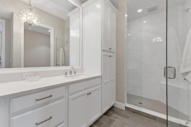 bathroom featuring an enclosed shower, a notable chandelier, and vanity