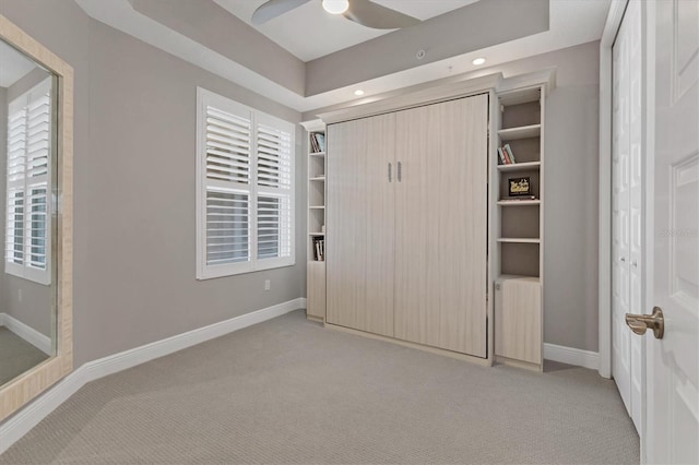 unfurnished bedroom featuring light carpet, radiator heating unit, ceiling fan, and a tray ceiling