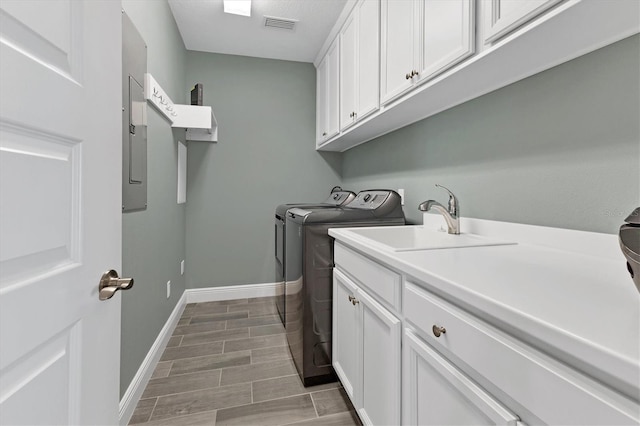 washroom with washing machine and dryer, a sink, cabinet space, visible vents, and baseboards