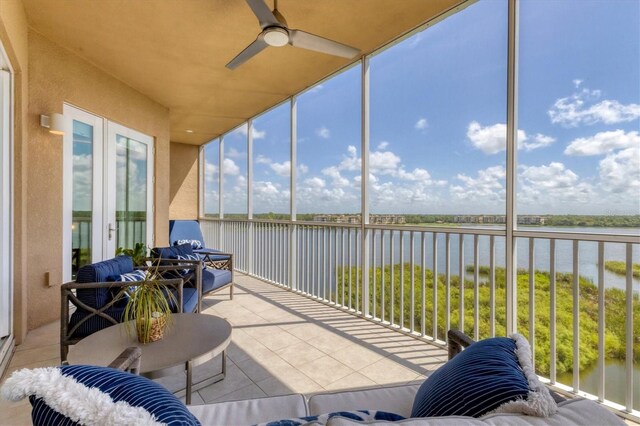 sunroom with a water view and ceiling fan