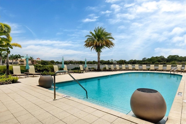 community pool with a patio area and fence