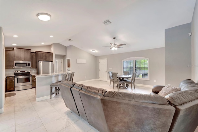 tiled living room featuring ceiling fan and vaulted ceiling