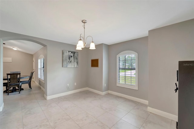 empty room featuring vaulted ceiling, light tile patterned floors, and an inviting chandelier