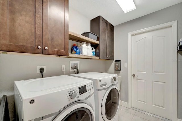 laundry area with light tile patterned flooring, cabinets, and washing machine and dryer