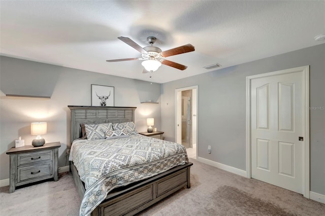 bedroom with connected bathroom, light colored carpet, and ceiling fan