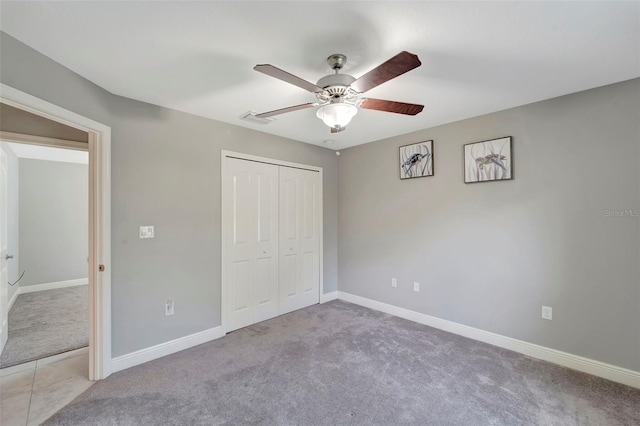 unfurnished bedroom with ceiling fan, light colored carpet, and a closet