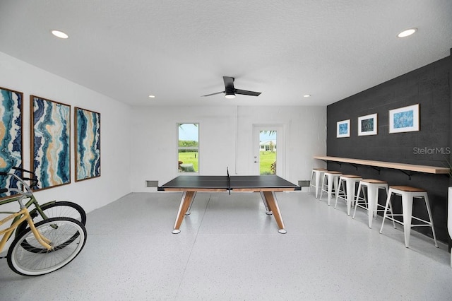 recreation room with a textured ceiling and ceiling fan