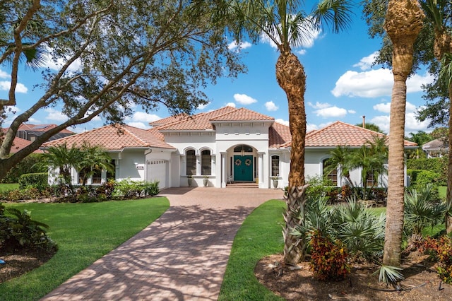 mediterranean / spanish-style house featuring a garage and a front lawn