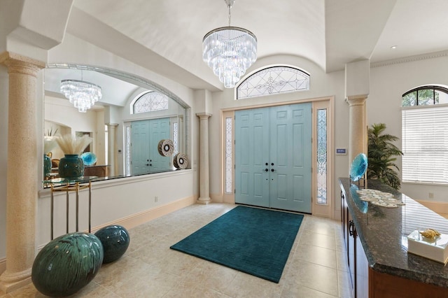 tiled foyer with decorative columns, an inviting chandelier, and lofted ceiling