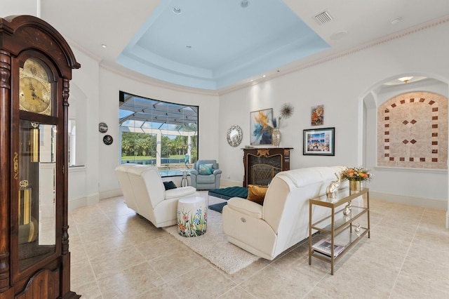 living room with a raised ceiling, a high end fireplace, and ornamental molding