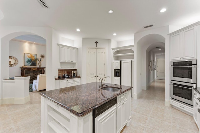 kitchen featuring white cabinets, sink, an island with sink, double oven, and dishwashing machine