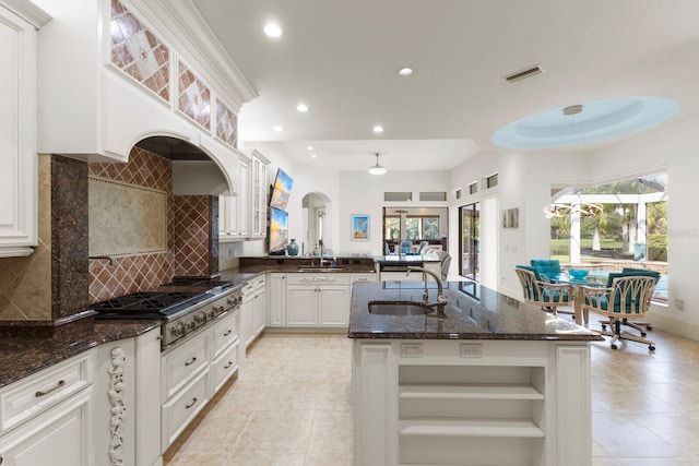 kitchen with decorative backsplash, stainless steel gas cooktop, sink, dark stone countertops, and white cabinets