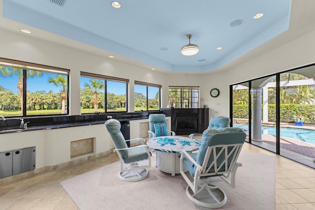 sitting room featuring plenty of natural light, a raised ceiling, and light tile patterned floors