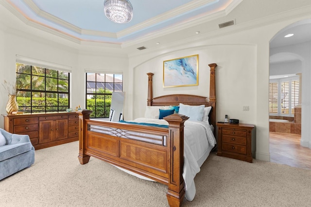 bedroom featuring crown molding, ensuite bath, a tray ceiling, a notable chandelier, and light colored carpet