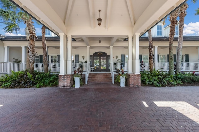 view of exterior entry featuring french doors and a porch