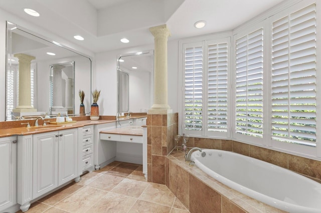 bathroom featuring tiled tub, tile patterned flooring, vanity, and ornate columns