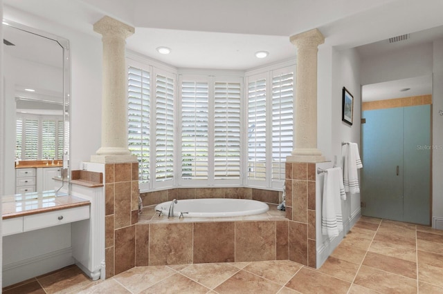 bathroom featuring vanity, decorative columns, and tiled tub