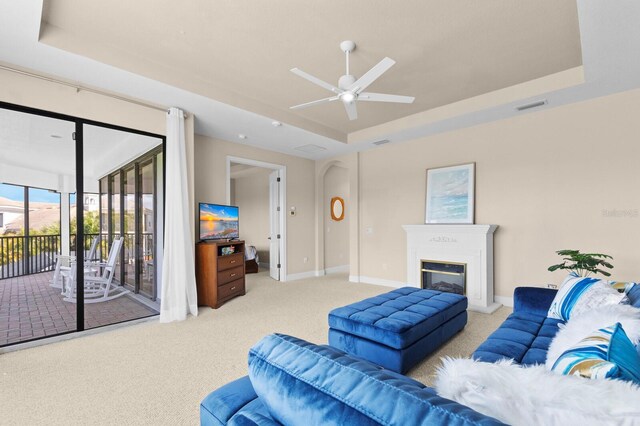 living room featuring light colored carpet, a raised ceiling, and ceiling fan