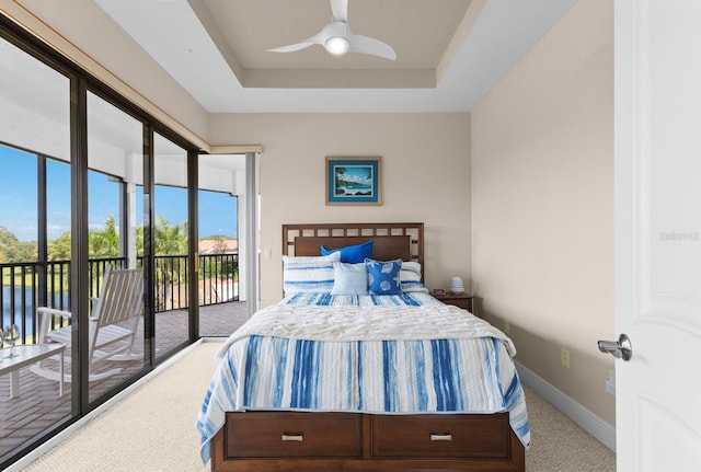 carpeted bedroom with a raised ceiling, ceiling fan, and access to exterior