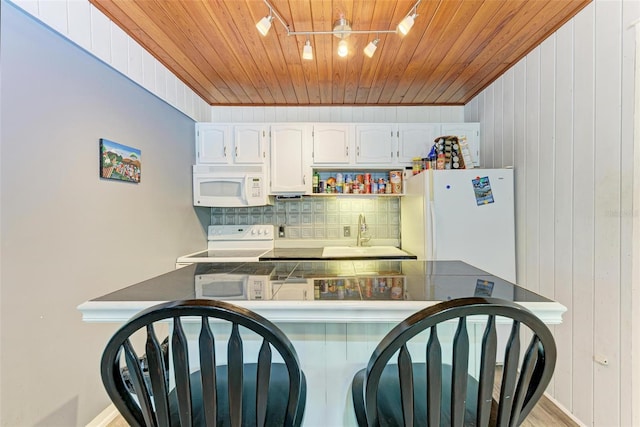 kitchen with white cabinetry, tasteful backsplash, white appliances, kitchen peninsula, and sink