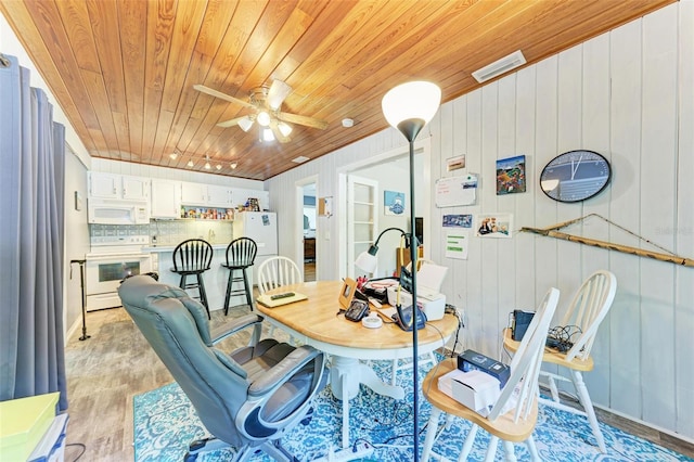 dining room with light hardwood / wood-style flooring, wood walls, ceiling fan, and wooden ceiling