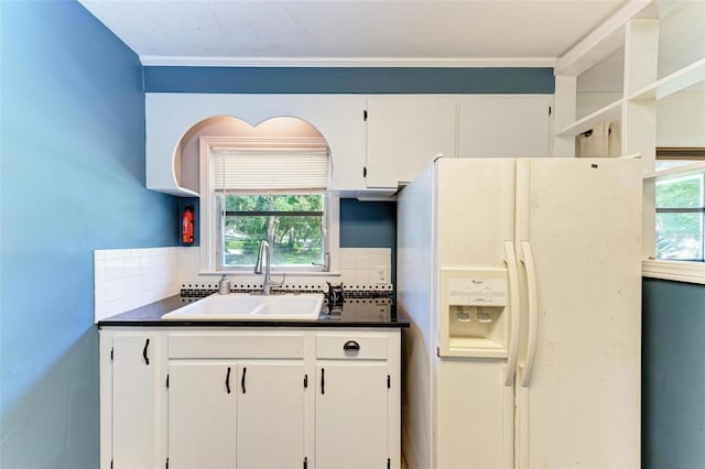 kitchen with decorative backsplash, white cabinets, white refrigerator with ice dispenser, and sink