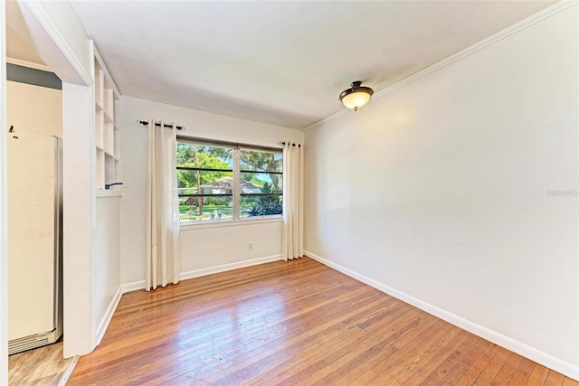 spare room with ornamental molding and light wood-type flooring