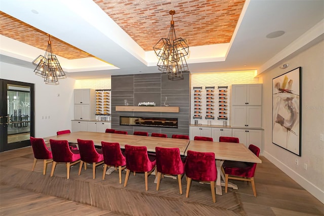 dining space featuring brick ceiling, a notable chandelier, a fireplace, and a tray ceiling