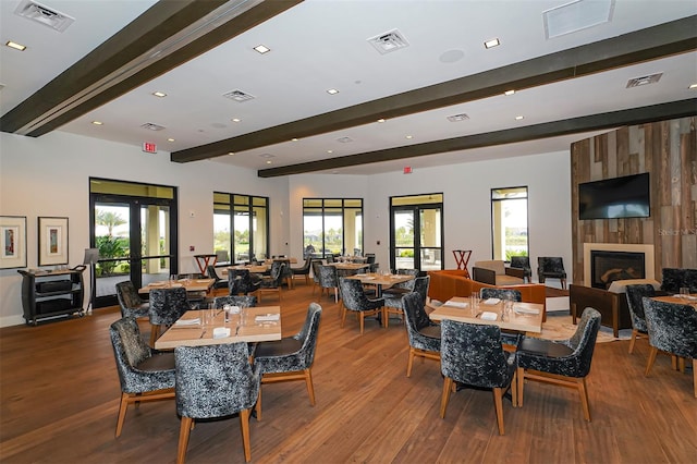 dining room featuring a large fireplace, wood-type flooring, beam ceiling, and french doors