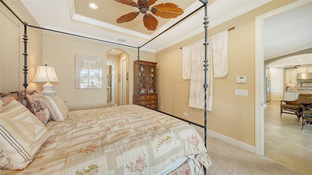 carpeted bedroom featuring ceiling fan, refrigerator, ornamental molding, and a tray ceiling