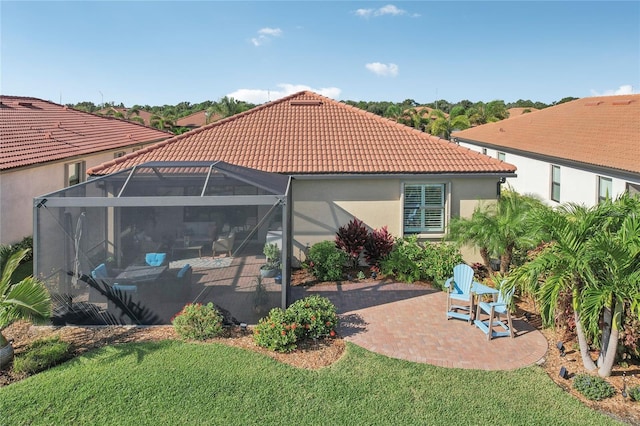 rear view of property featuring a yard, a patio, and glass enclosure