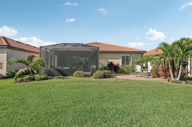 rear view of house featuring a yard, a patio area, and a lanai