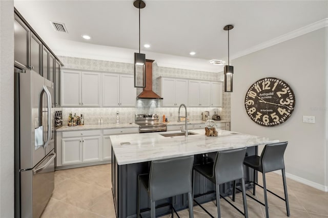 kitchen with a center island with sink, white cabinets, sink, ornamental molding, and appliances with stainless steel finishes