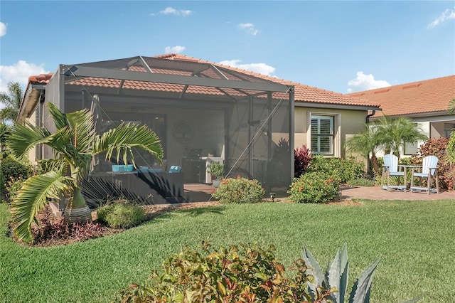 back of house featuring glass enclosure, a patio area, and a yard