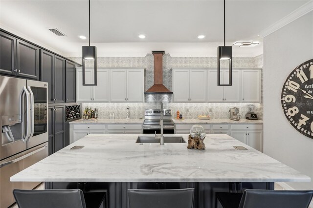 kitchen with a center island with sink, decorative light fixtures, wall chimney range hood, and stainless steel appliances