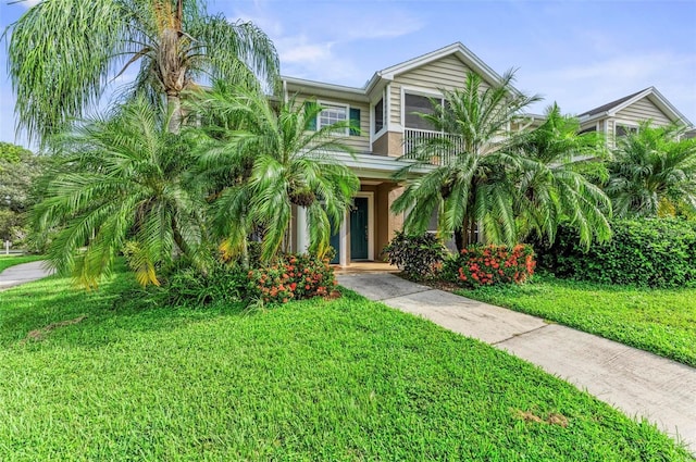 view of front of house with a front yard, a balcony, and stucco siding