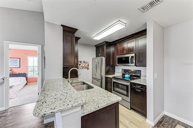 kitchen with light wood-type flooring, dark brown cabinets, visible vents, a sink, and stainless steel appliances