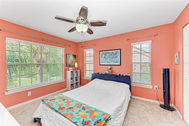 bedroom featuring ceiling fan, baseboards, multiple windows, and carpet floors