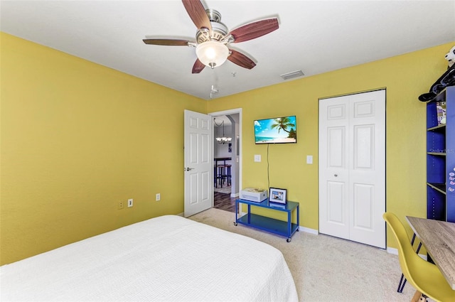 bedroom with a closet, light colored carpet, a ceiling fan, visible vents, and baseboards