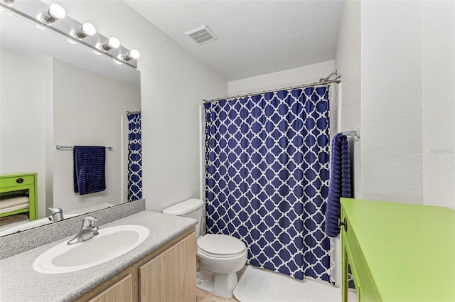 bathroom with toilet, vanity, a textured wall, and visible vents