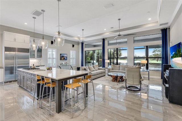 kitchen with hanging light fixtures, white cabinetry, appliances with stainless steel finishes, a breakfast bar, and light stone countertops