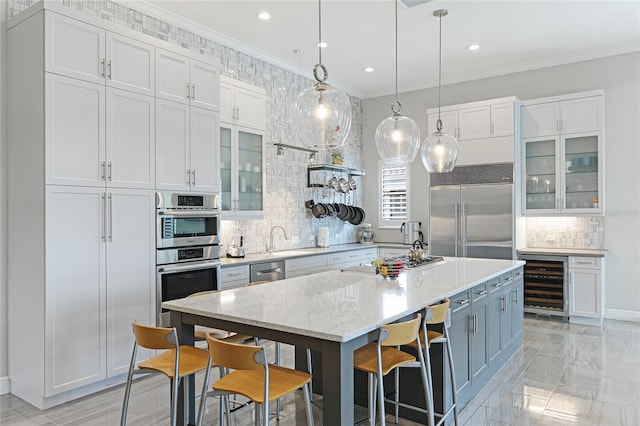 kitchen with stainless steel appliances, wine cooler, white cabinetry, and a kitchen island with sink