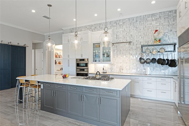 kitchen featuring stainless steel appliances, white cabinetry, a center island, and a barn door